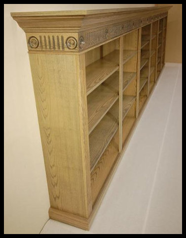 A 20-foot custom modular bookcase handcrafted in three sections for portability, featuring fluted moldings, decorative rosettes, and a solid wood tabletop.