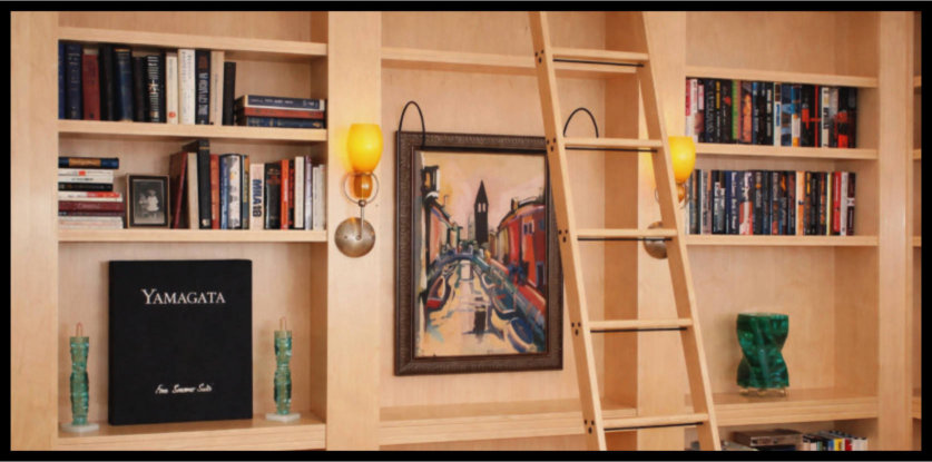 Custom L shaped maple bookcase with rolling ladder and sconce lights.